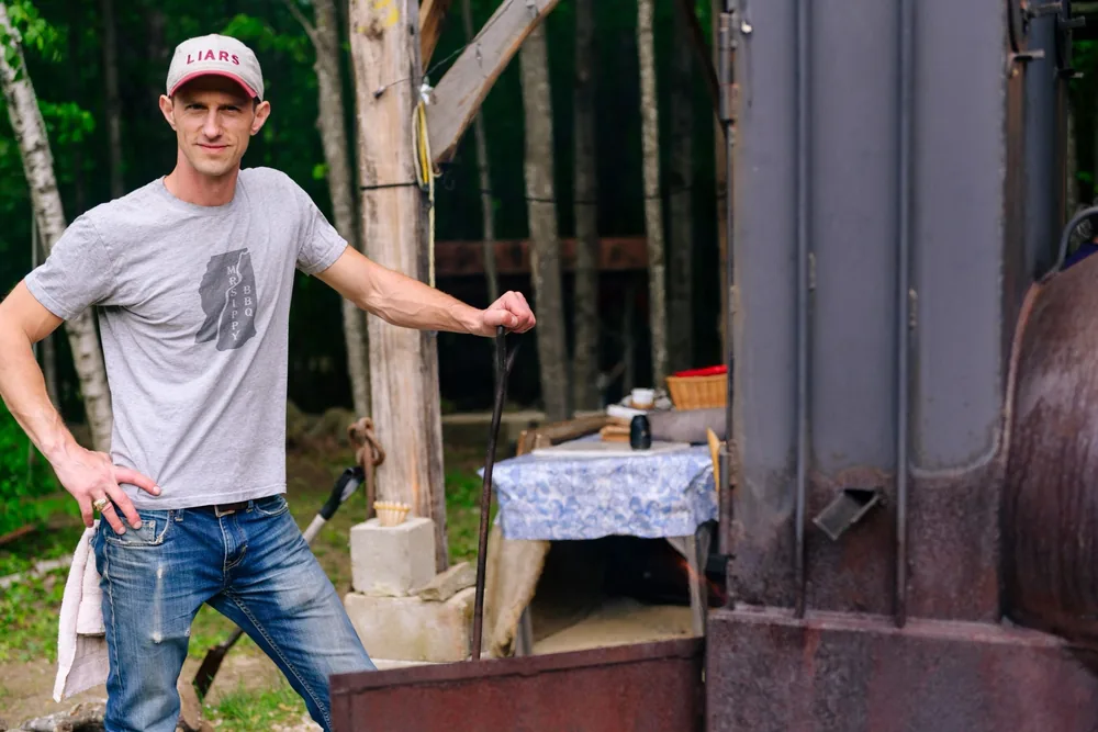 Cecil Abels III leaning on the Lang smoker in a MrSippy tee